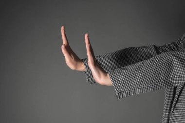 Kadın eli, gri arkaplanda dur işareti gösteriyor..