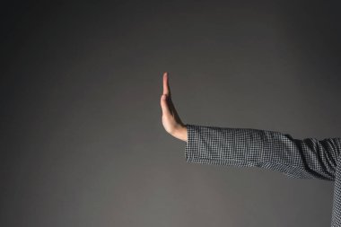 Kadın eli, gri arkaplanda dur işareti gösteriyor..