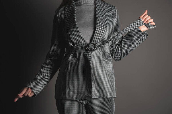 Woman in the gray suit is posing on the gray background.