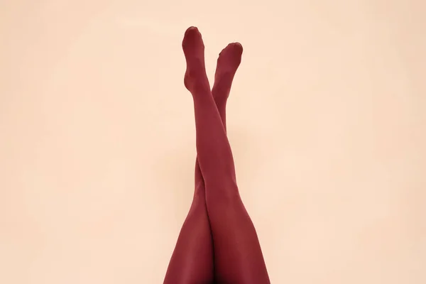 Woman raised up legs in the red stockings on the light background.