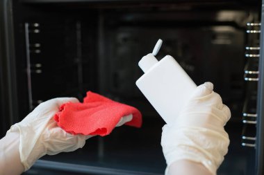 Kadın mutfak sobasını deterjanın yanında yıkıyor..