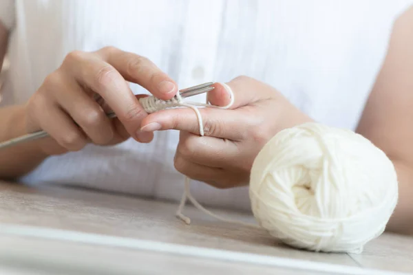 A woman is knitting with the knitting needle close up.