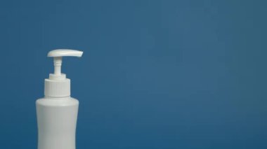 Mavi arka planda antiseptik jel kullanan eller..
