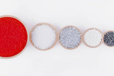 Beyaz arka planda tahta kaplarda farklı renklerde polimer ürünler. Polimerler ve polistiren. Kimya endüstrisi