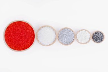 Beyaz arka planda tahta kaplarda farklı renklerde polimer ürünler. Polimerler ve polistiren. Kimya endüstrisi