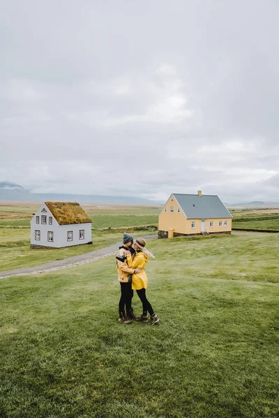 Casal encantador em roupas amarelas olhando para as casas de relva na fazenda icelandic Glaumbaer. Islândia destino de viagem. — Fotografia de Stock