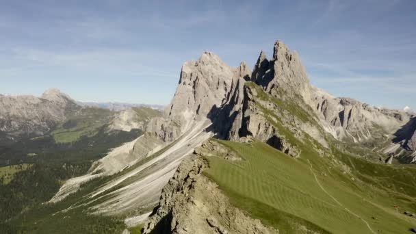 Een prachtig uitzicht vanaf de drone naar de attractie van de Dolomieten - Mount Seceda. Een groene open plek met een afgrond tegen de achtergrond van gigantische en enorme rotsen. en de blauwe lucht. — Stockvideo