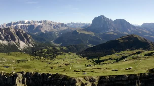 Una hermosa vista desde el avión no tripulado a la atracción de los Dolomitas Monte Seceda. Un claro verde con un precipicio contra el telón de fondo de rocas gigantes y enormes. y el cielo azul. — Vídeos de Stock