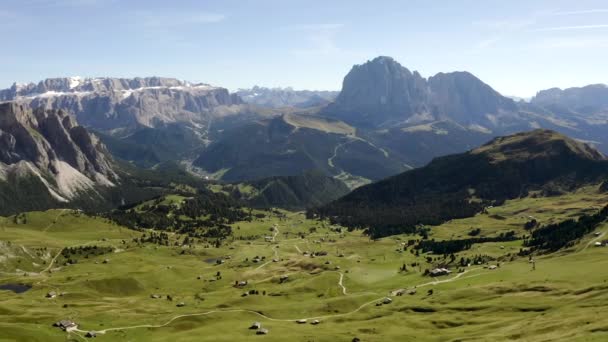 Uma vista deslumbrante do drone para a atração das Dolomitas Monte Seceda. Uma clareira verde com um precipício contra o pano de fundo de rochas gigantes e enormes. e o céu azul. — Vídeo de Stock
