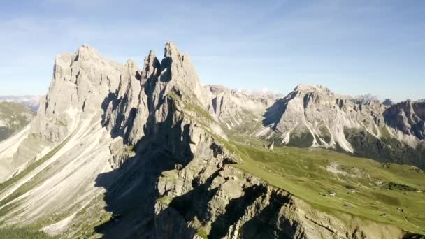 Uma vista deslumbrante do drone para a atração das Dolomitas Monte Seceda. Uma clareira verde com um precipício contra o pano de fundo de rochas gigantes e enormes. e o céu azul. — Vídeo de Stock