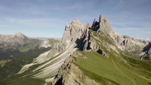 Een prachtig uitzicht vanaf de drone naar de attractie van de Dolomieten - Mount Seceda. Een groene open plek met een afgrond tegen de achtergrond van gigantische en enorme rotsen. en de blauwe lucht. — Stockvideo