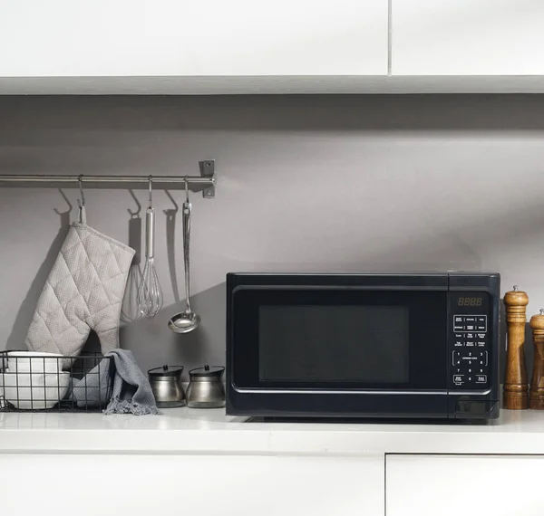 Black microwave in the kitchen with kitchen accessories