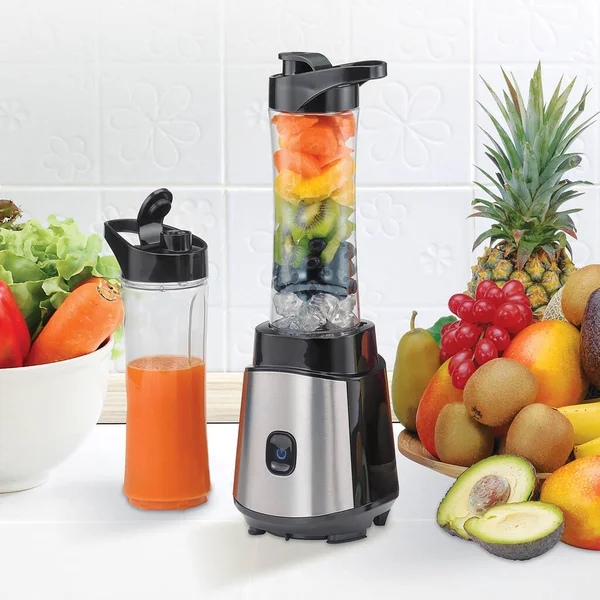 Blender on a kitchen table with fruits and smoothies