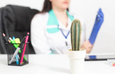 Büyük bir kaktüs eldiven takan bir doktorun arka planında duruyor. Rektal ağrı, hemoroid, anal kaşıntı, proktoloji kavramı.