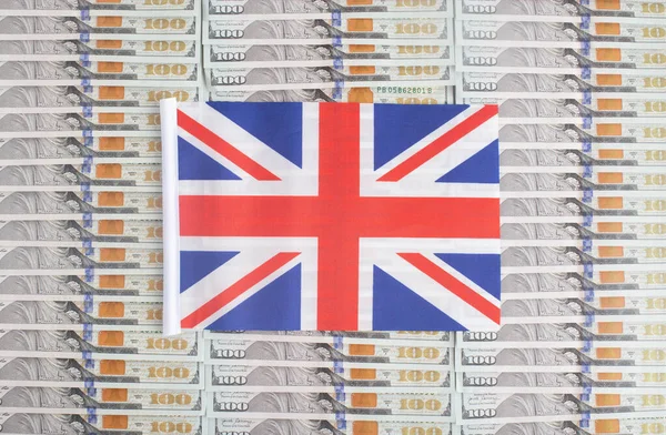 United Kingdom flag on a background from dollar banknotes. Concept of the relationship of the British money in relation to the dollar, the countrys economy, financial — Stock Photo, Image