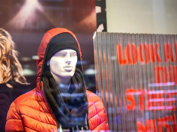 现代商店里的男性人体模特，穿着一件头罩和围巾的夹克。关于销售秋冬时尚服饰、背景的概念 — 图库照片