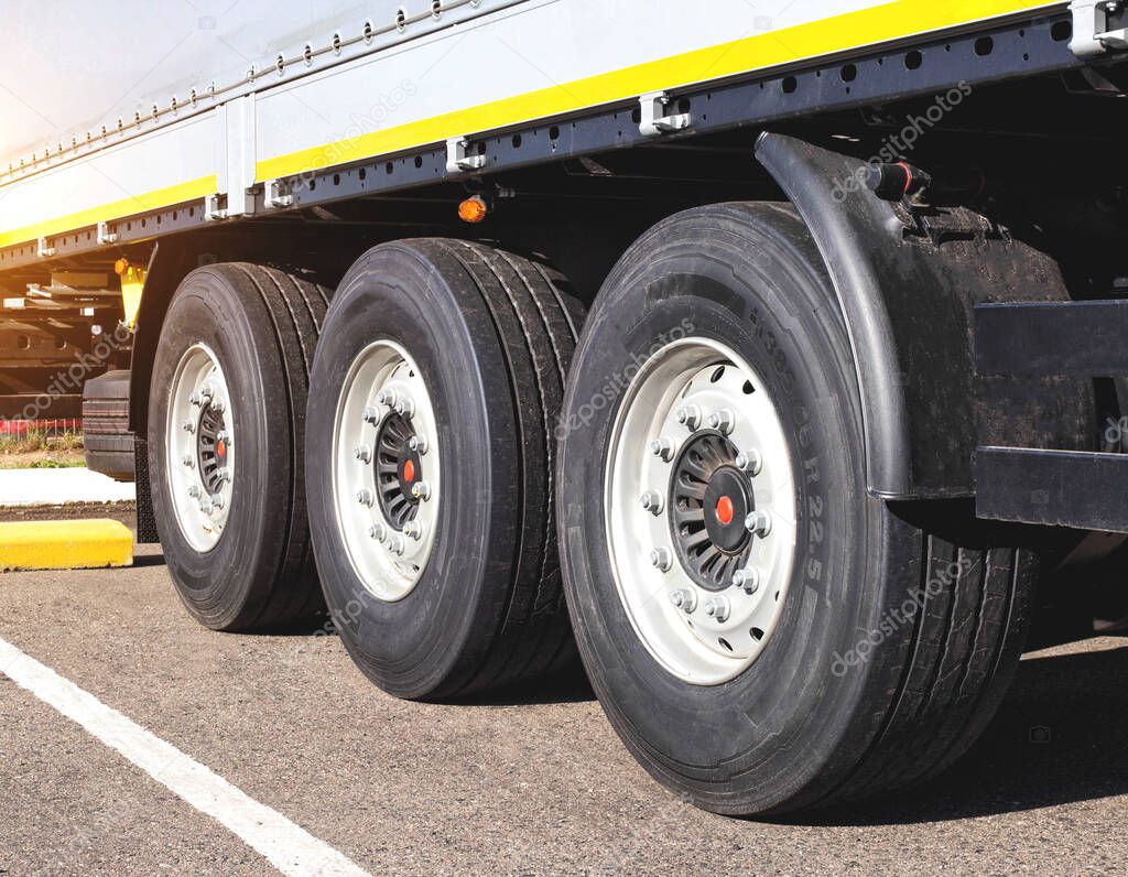 Wheels with rubber on the cargo 3-axle trailer of the tractor. The concept of choosing high-quality rubber for road transport. Fuel economy and road safety, parameters