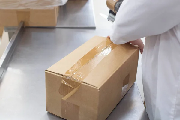 worker packs boxes with products in a factory, industry.
