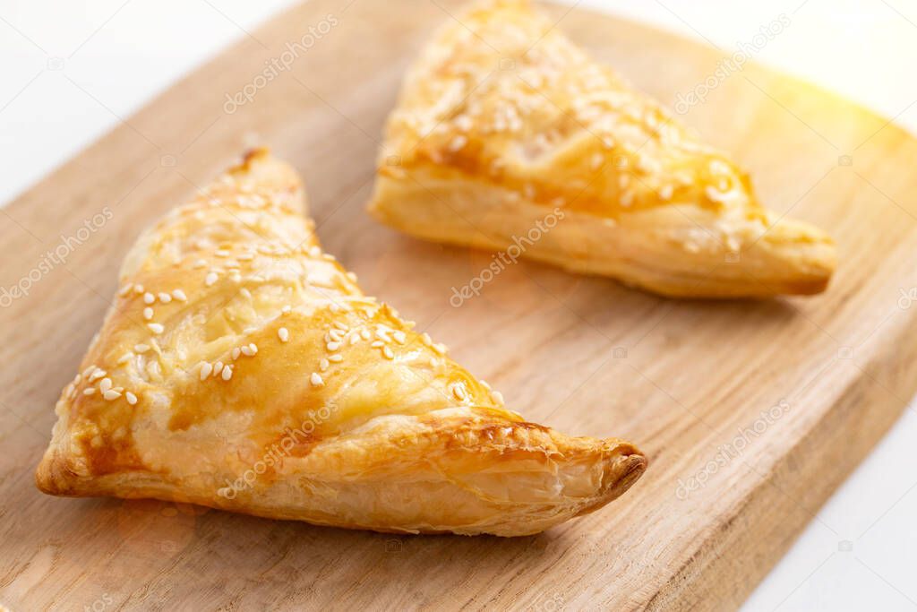 Golden crispy slices with ham and cheese on wooden kitchen board, close-up