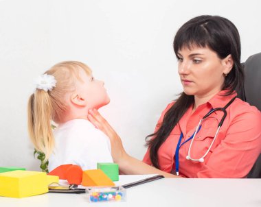 Pediatrik bir otolarolog doktor 3 yaşındaki küçük bir kızın boğazındaki bademcikleri inceliyor. Çocuklarda boğaz ağrısı, gırtlak iltihabı ve bademcik iltihabı tedavisi.
