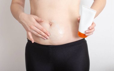 Bir kız sorunlu bölgelerde, metabolizmada yağ yakmak için midesine anti-selülit termo kremi sürüyor.