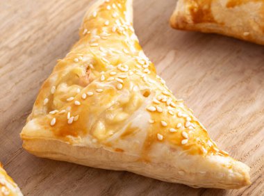 Ahşap mutfak tahtasının üzerinde jambon ve peynirli altın kıtır dilimler, yakın plan.