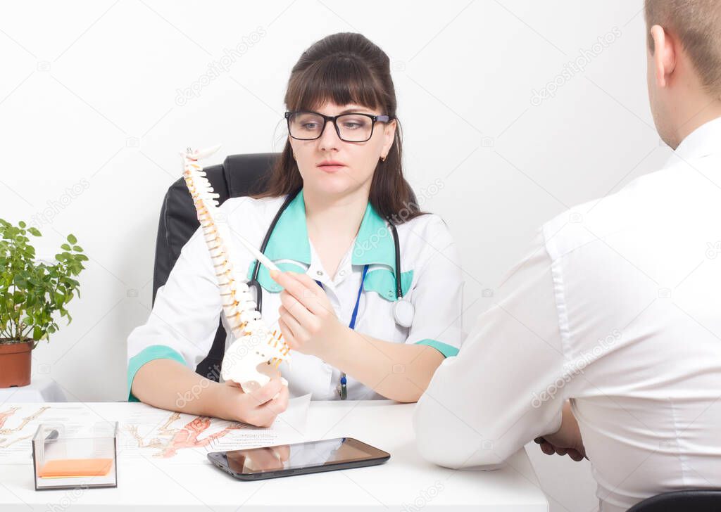 The doctor explains to the patient on the layout of the spine how the modern surgery on the wound will be performed laser puncture for protrusion and herniated discs, deformities