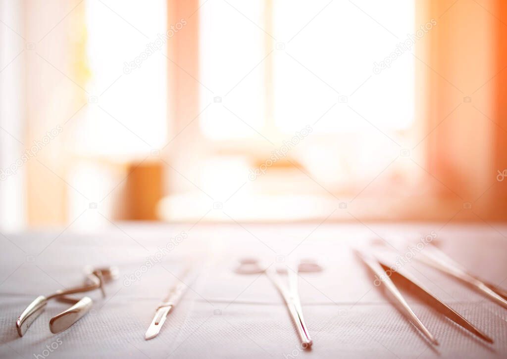 Surgical instruments on the table in the operating room of the hospital. Sunny sunset in the window. Surgery concept, amputation, complications after surgery. Copy space for text, transplant