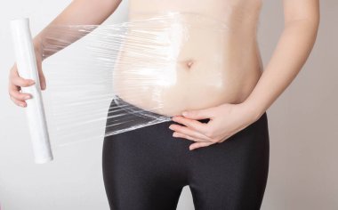 Kız evde karnına anti-selülit sargısı yapıyor. Su tuzu metabolizmasını deri altı adipoz dokusu ve sıvı çıkışında iyileştirme kavramı