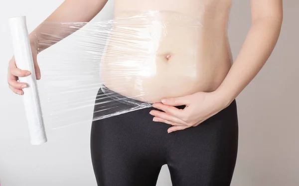 女の子は自宅で胃の上に抗セルライトラップを作る 皮下脂肪組織の水塩代謝の改善と流体の流出のための概念 — ストック写真