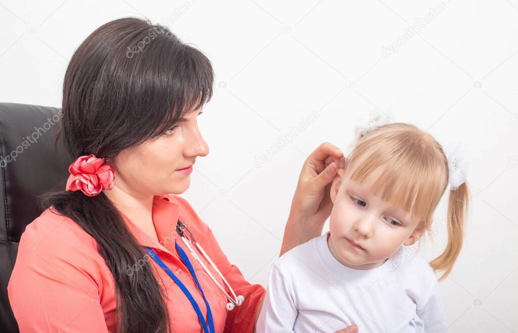 Doctor pediatric otolaryngologist examines the ear of a child of a little girl whose sulfur plug in the ear, background, plugging