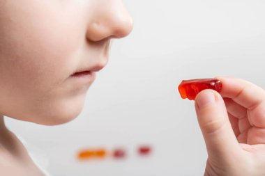 Küçük bir kız, ayı şeklinde vitamin yiyor. Multivitamin kompleksleriyle çocuk sağlığını güçlendirme kavramı. Yakın plan, lezzetli, B-6 vitamini.