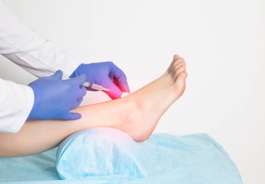Doktor, bağları kopmuş ve yaralanmış bir hastaya yakın çekim sırasında eklem içi enjeksiyon yapıyor. Ozon terapisi