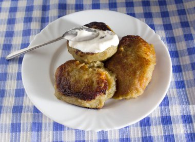 Belarus usulü patatesli krep, et ve ekşi krema. Mavi kareli arkaplan, yakın plan