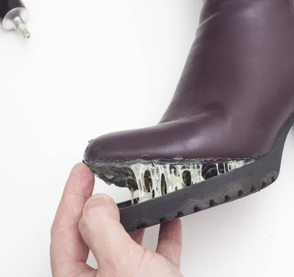 A shoe repairman glues the sole of a women\'s winter boot. Low-quality shoes concept, boots repair