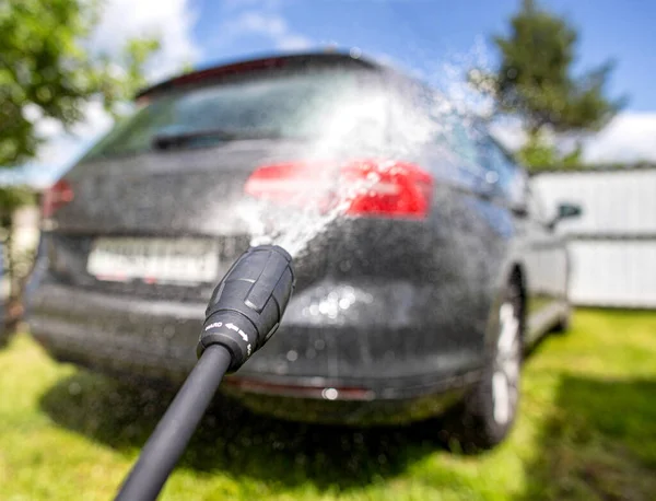 Car wash with modern car shampoo using a high pressure washer in summer. Background, cleaning cars from dirt, reflection