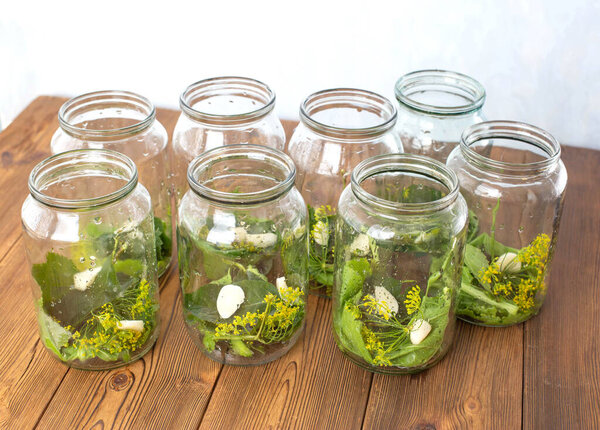 Банки со специями, чесноком и огурцами для сохранения огурцов. Банки со специями на деревянном фоне, сохранение на зиму