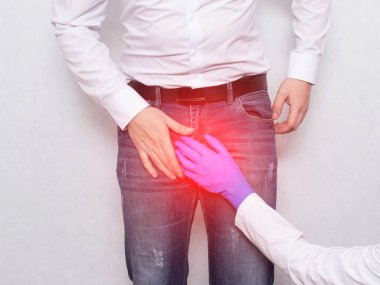 Tıbbi eldivenli bir doktor, erkek bir hastanın kasık bölgesine tutunur. Erkeklerde üreme hastalıkları, değişken ve prostatit kavramı, hipotermi