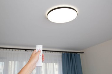 Kontrol paneli kapalı modern LED tavan avizesi. Odadaki ışığın parlaklığını ayarlıyorum.