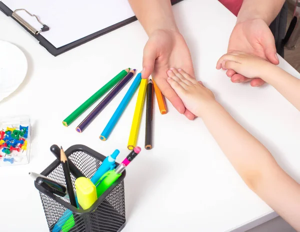 Руки взрослого и ребенка на столе с разноцветными карандашами. Концепция психологической помощи детям, развитие стрессоустойчивости — стоковое фото