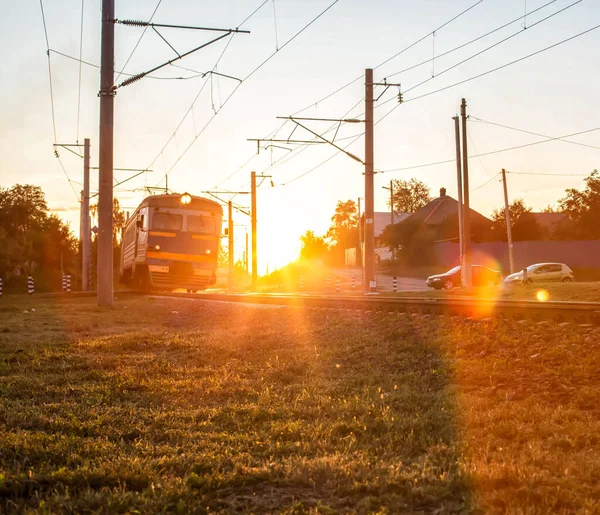 Tren paseos en el ferrocarril y cruza el cruce de ferrocarril en el fondo de una puesta de sol soleado, fondo. Industria — Foto de Stock