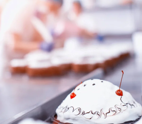 Mass production of cakes and sweets at the confectionery factory. Chefs make cakes of fresh berries and biscuit, food industry, copy space