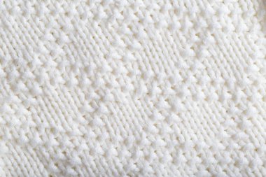 Beyaz ipliklerden örülmüş, rahat bir süveter. Makro, el yapımı.