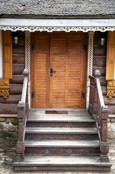 Wooden porch with steps and a door to a log cabin. Village houses architecture