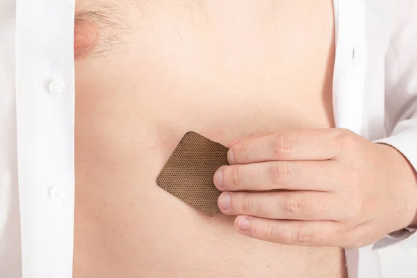 A man sticks an anti-nicotine patch on his stomach to quit the bad habit of spinning