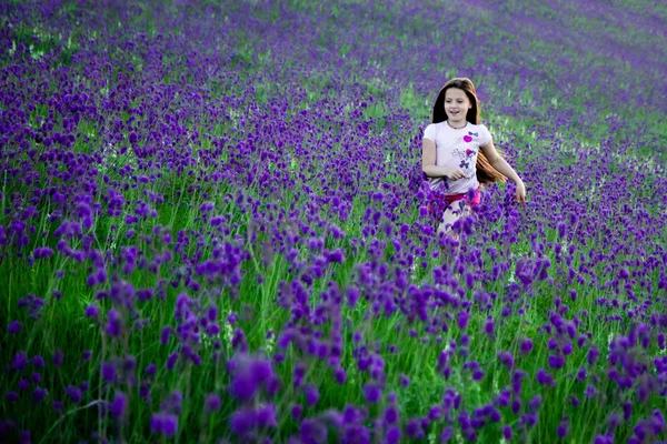 Meisje loopt door een gebied van wilde bloemen — Stockfoto