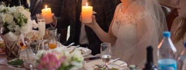 Gelin ve damat bir restoranda ellerinde mum tutuyorlar.