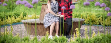 Parktaki bankta çiçeklerin arasında birbirini seven bir çift