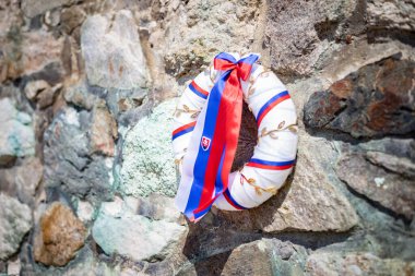 Taş duvarında Slovak bayrağı olan bir çelenk.