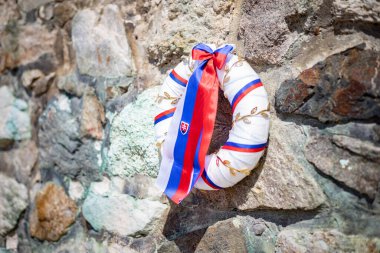 Taş duvarında Slovak bayrağı olan bir çelenk.